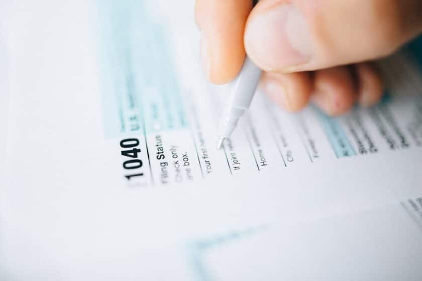 hand holding pen filling out 1040 tax document